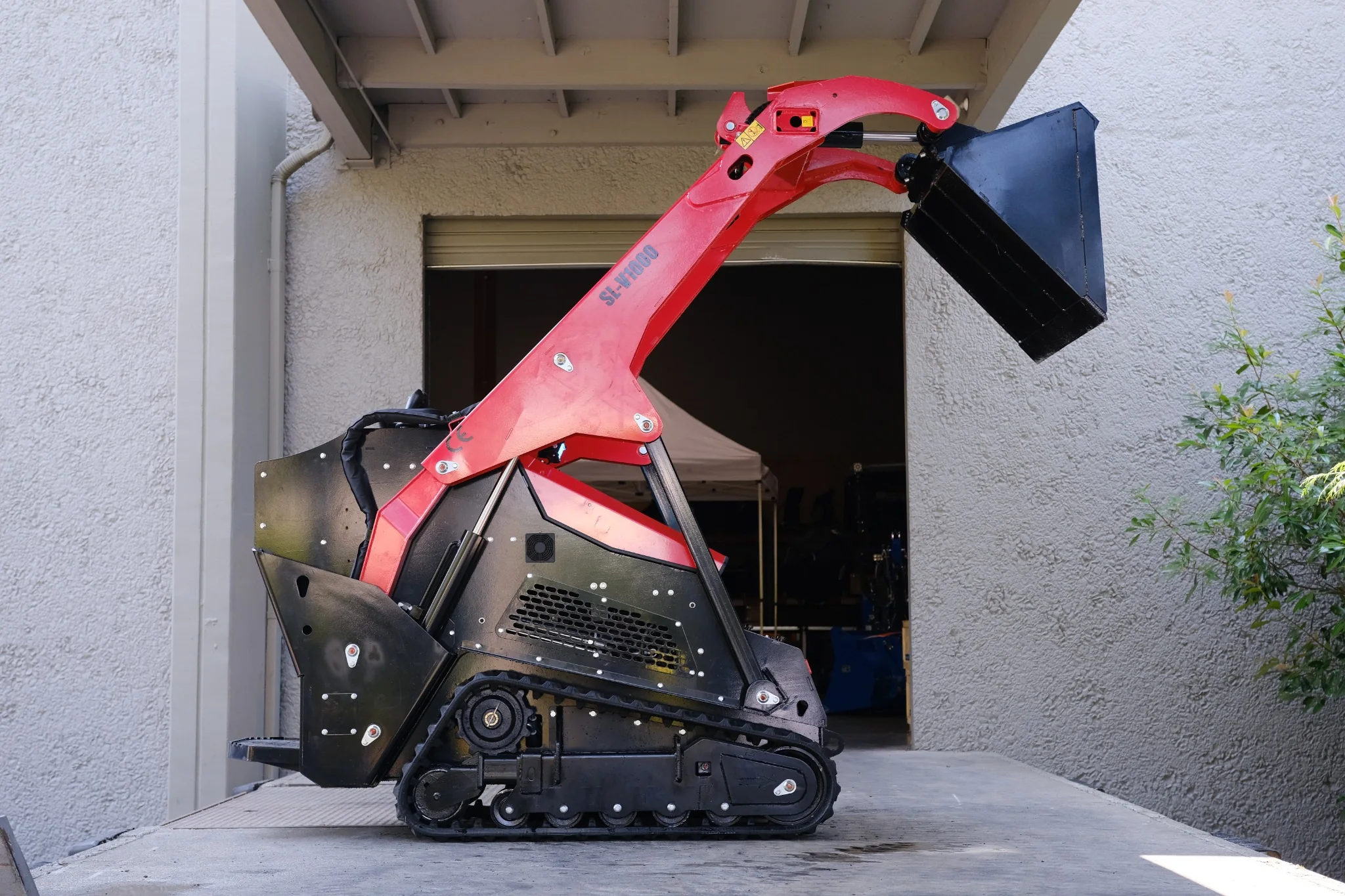 Side profile of the SDLOOL SL-V1000 compact tracked loader with the bucket fully raised.